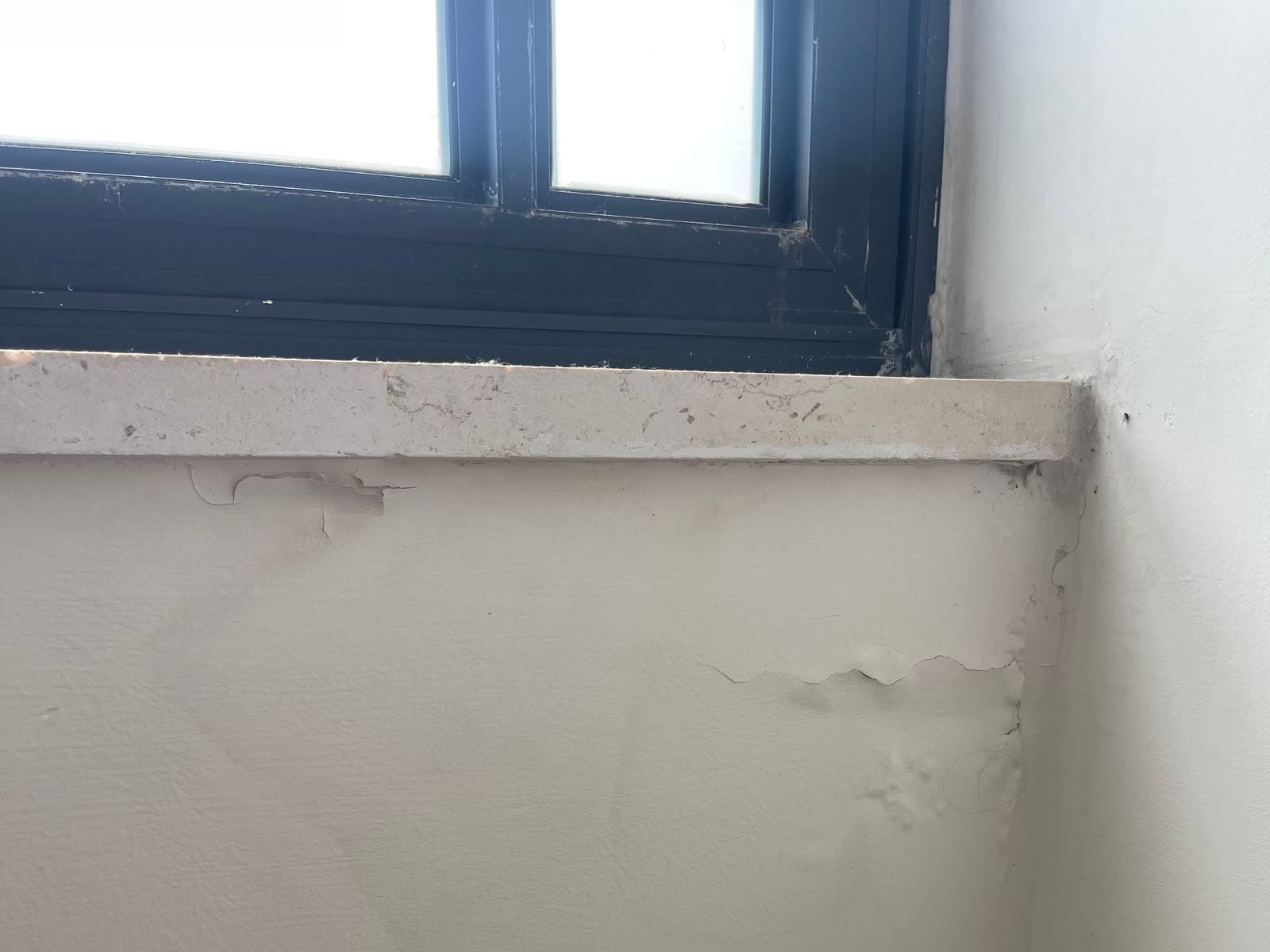 קיר מתחת לאדן חלון עם צבע מתקלף וסדק אנכי בפינה